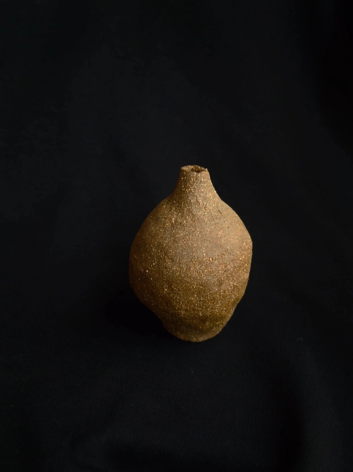Handcrafted rustic ceramic vase with textured surface on black background