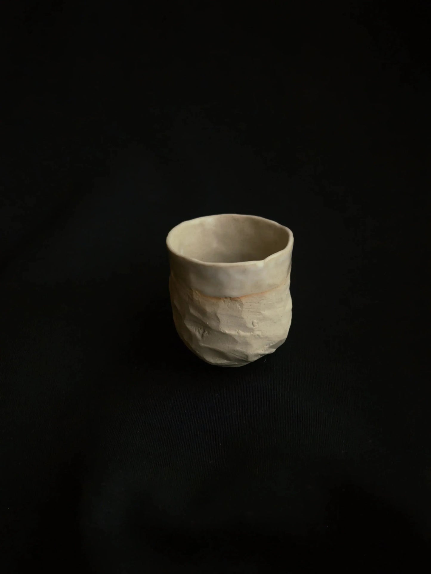 Handcrafted ceramic cup with textured surface on a dark background