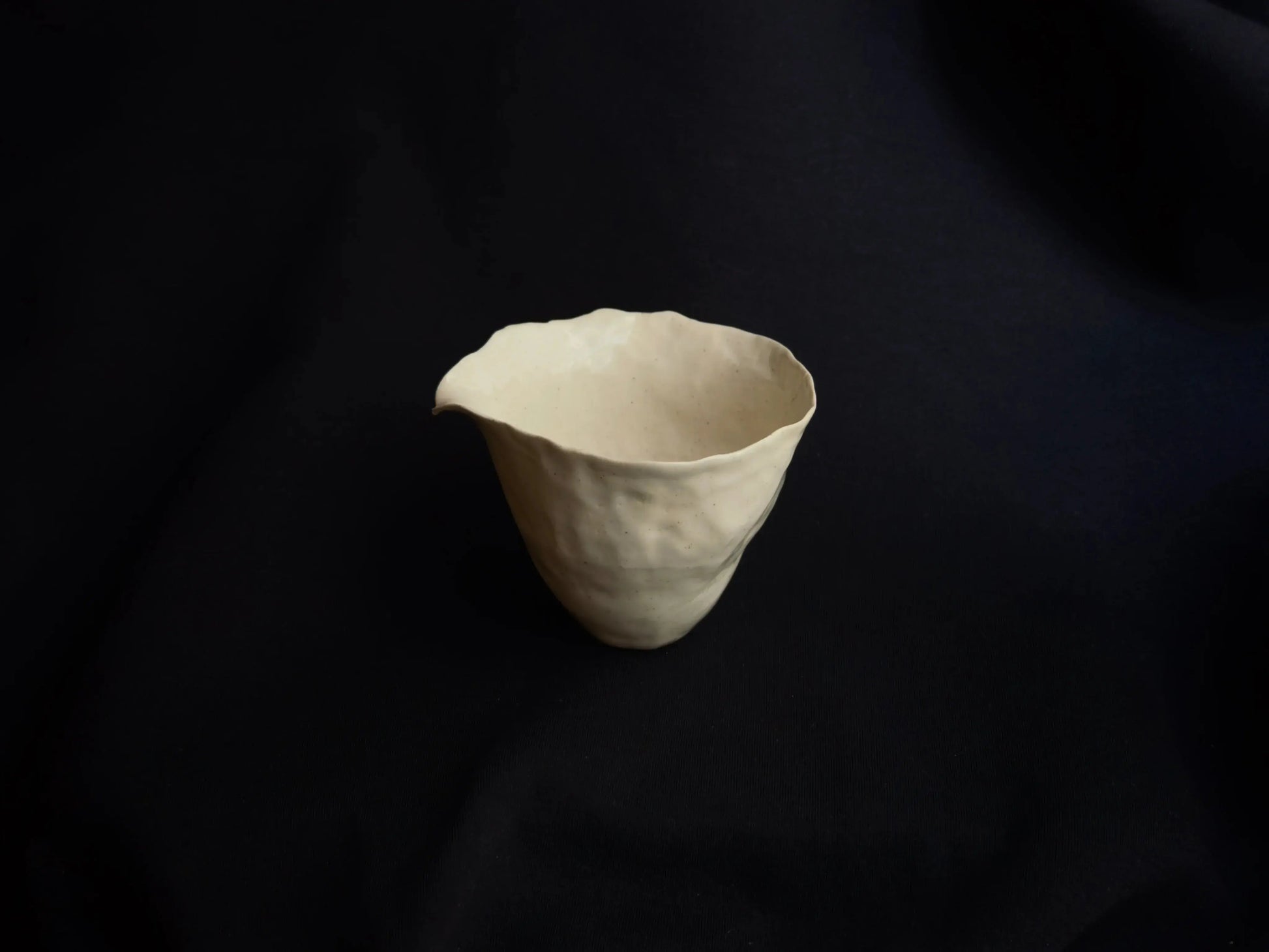 Handcrafted minimalist ceramic bowl with organic shape on a black background