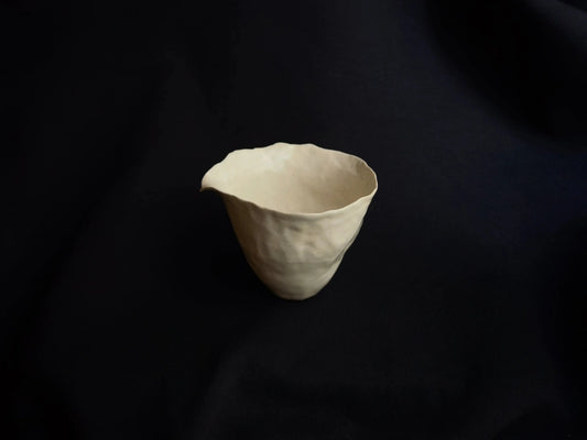 Handcrafted minimalist ceramic bowl with organic shape on a black background