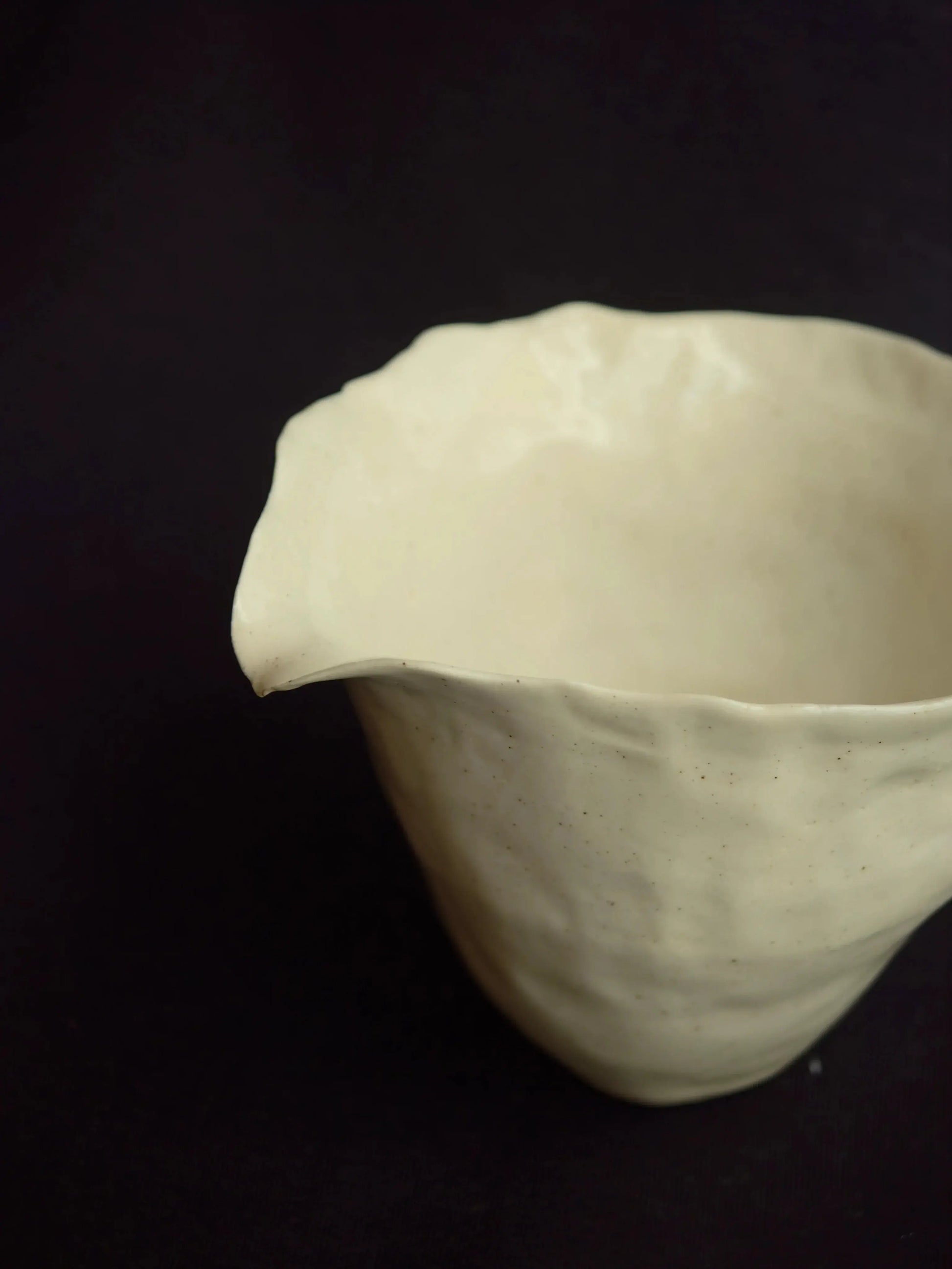Handcrafted ceramic pitcher with organic shape on a dark background