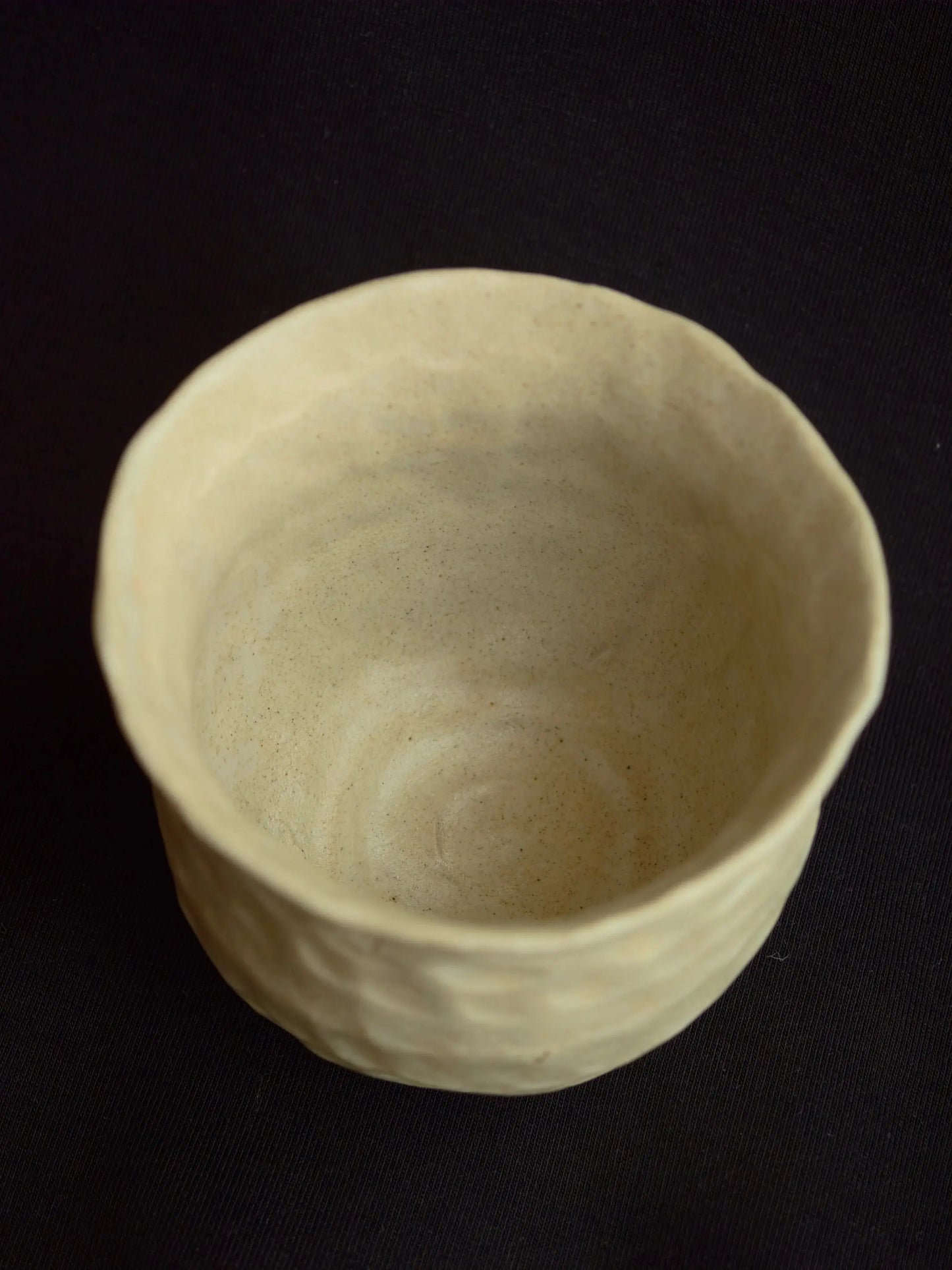 Handcrafted minimalist ceramic bowl with natural texture on a dark background