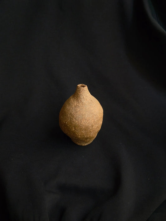 Handcrafted textured ceramic vase on black fabric background, minimalistic decor