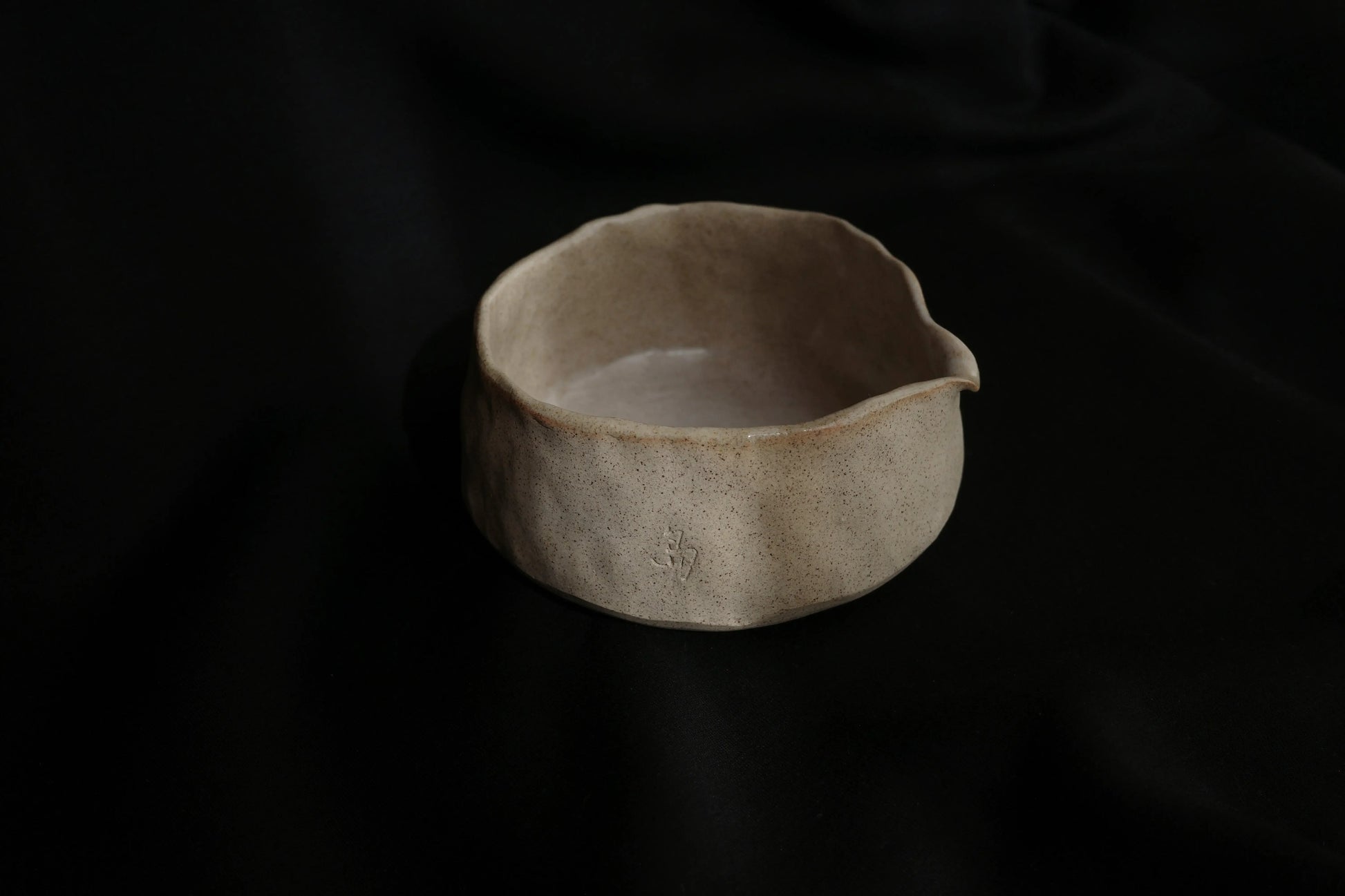 Handcrafted ceramic bowl with organic, minimal shape on a black background