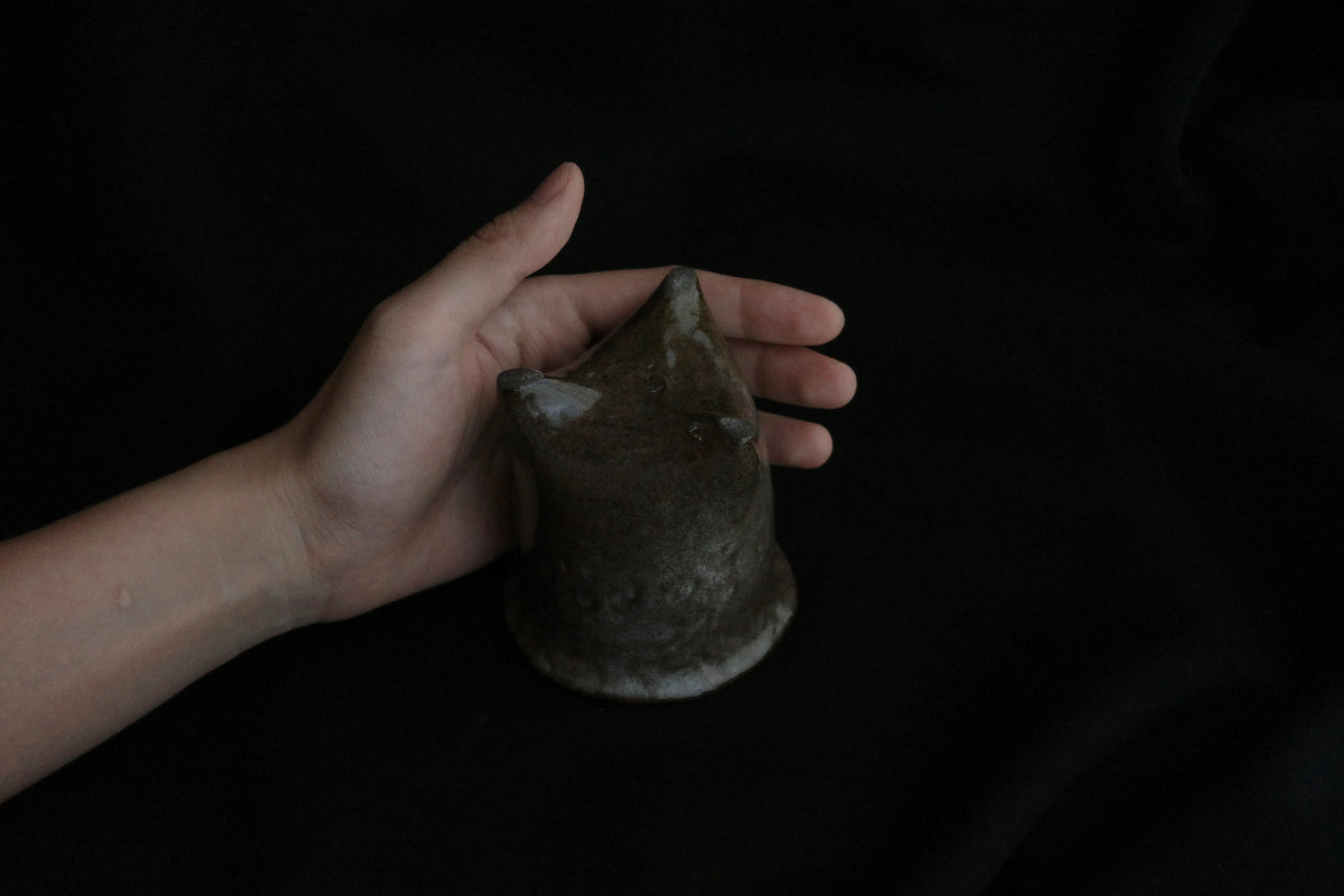 Hand holding a handcrafted ceramic cup with a unique textured, organic shape