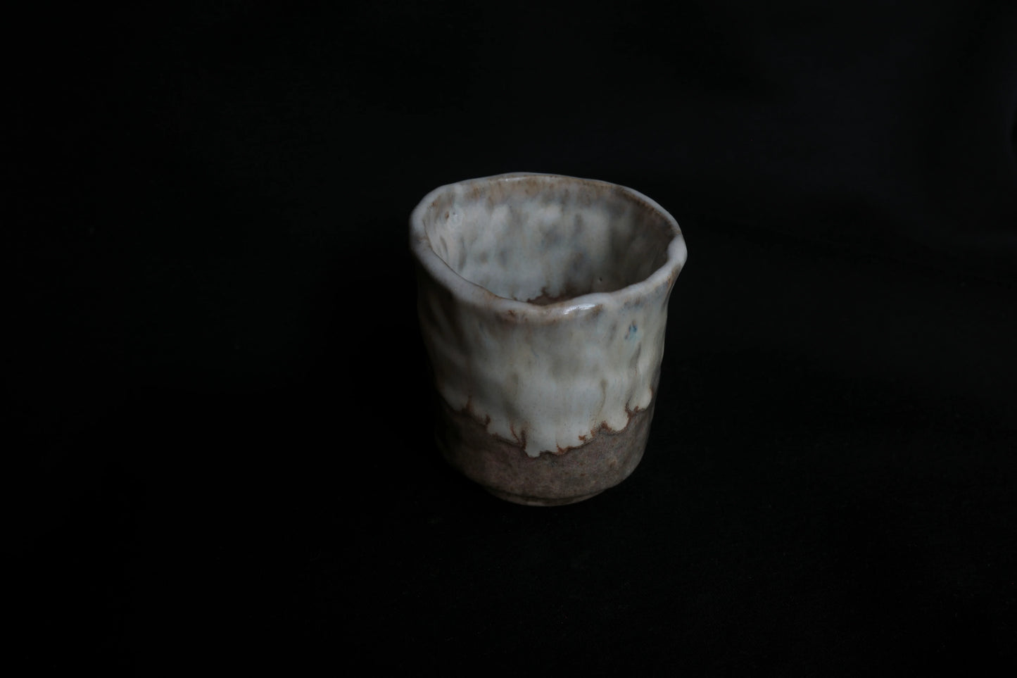 Handcrafted ceramic cup with textured glaze on a dark background