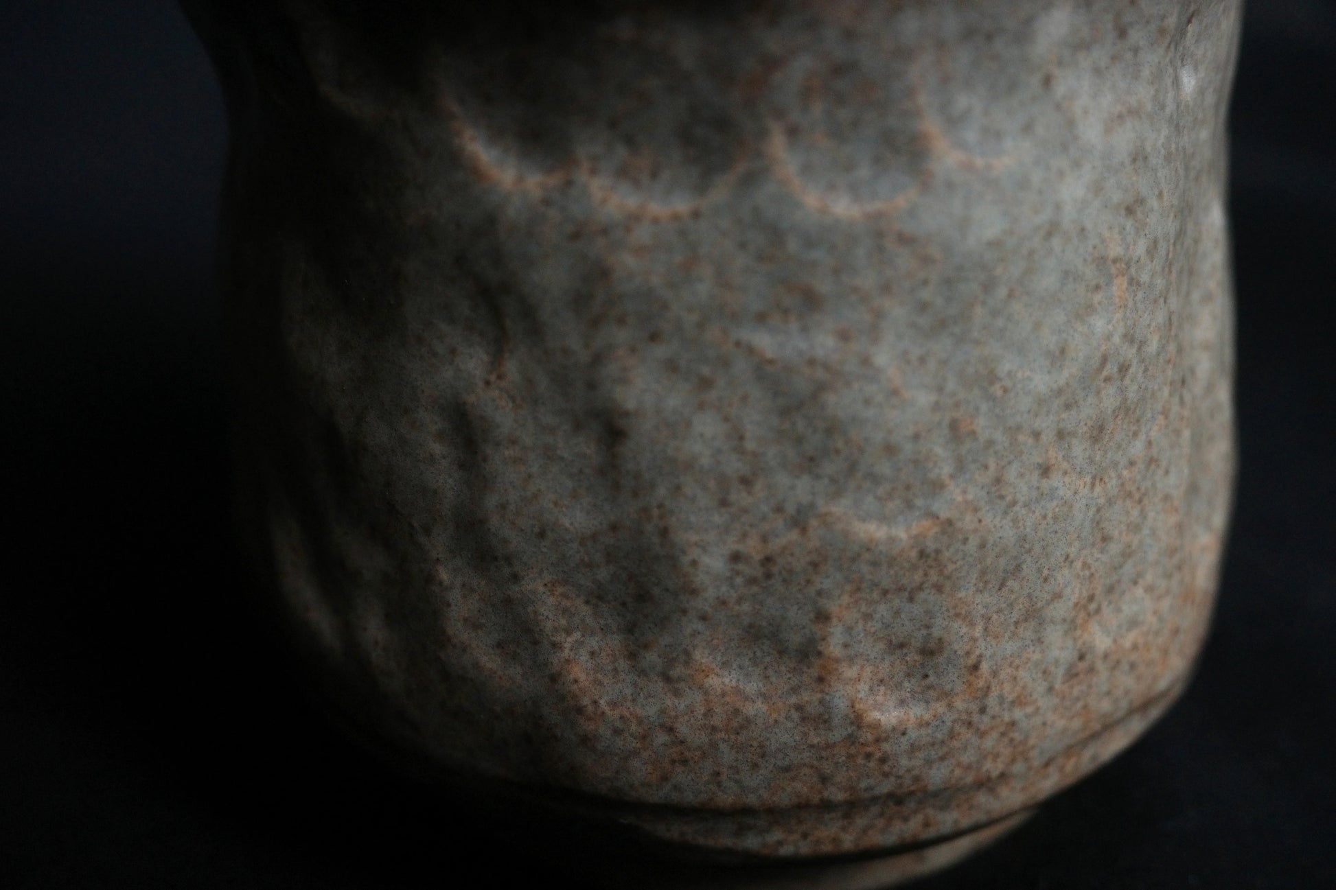 Close-up of handcrafted ceramic vase with textured, speckled gray and brown surface