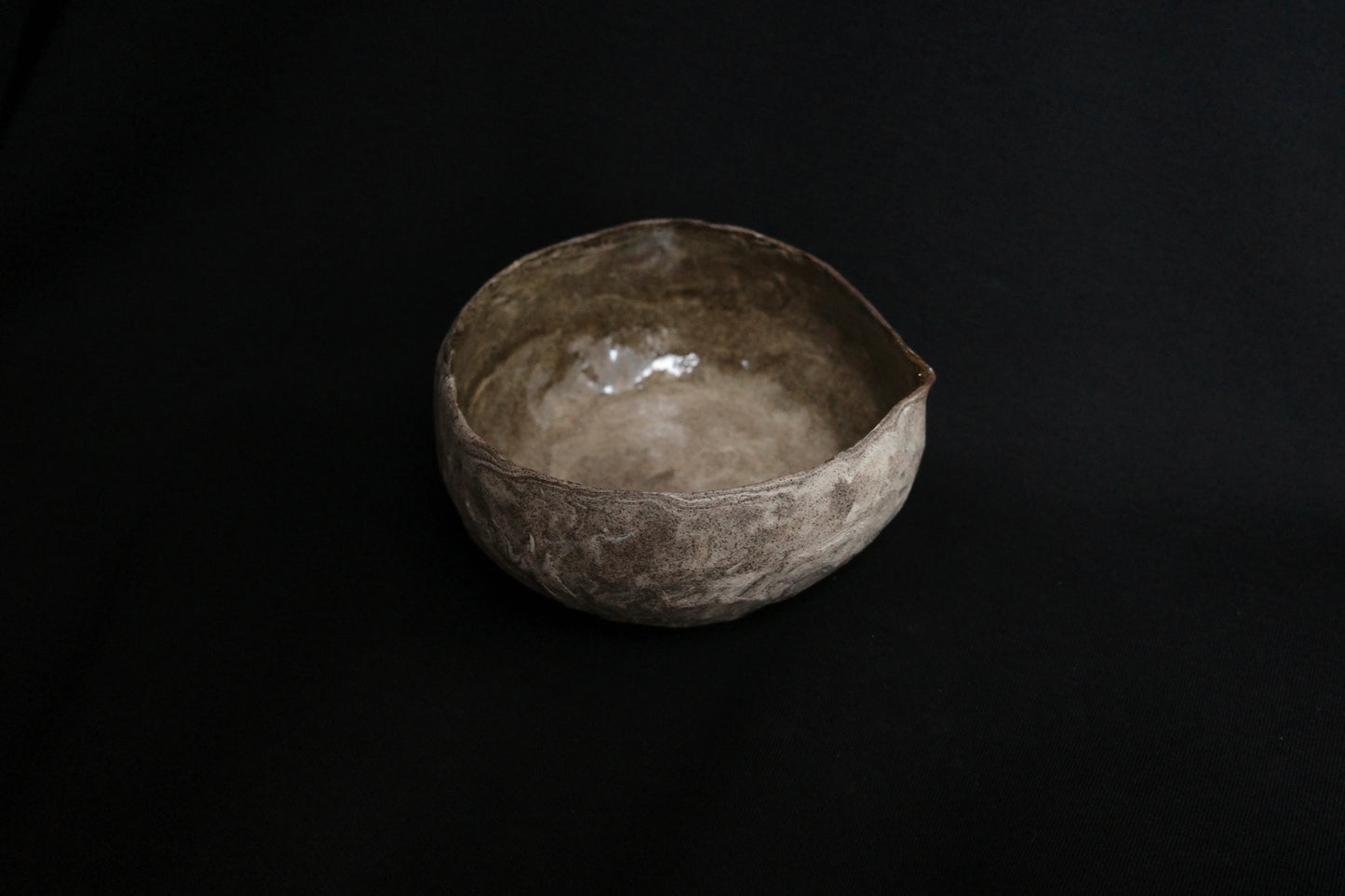 Handcrafted ceramic bowl with rustic, textured finish on a black background
