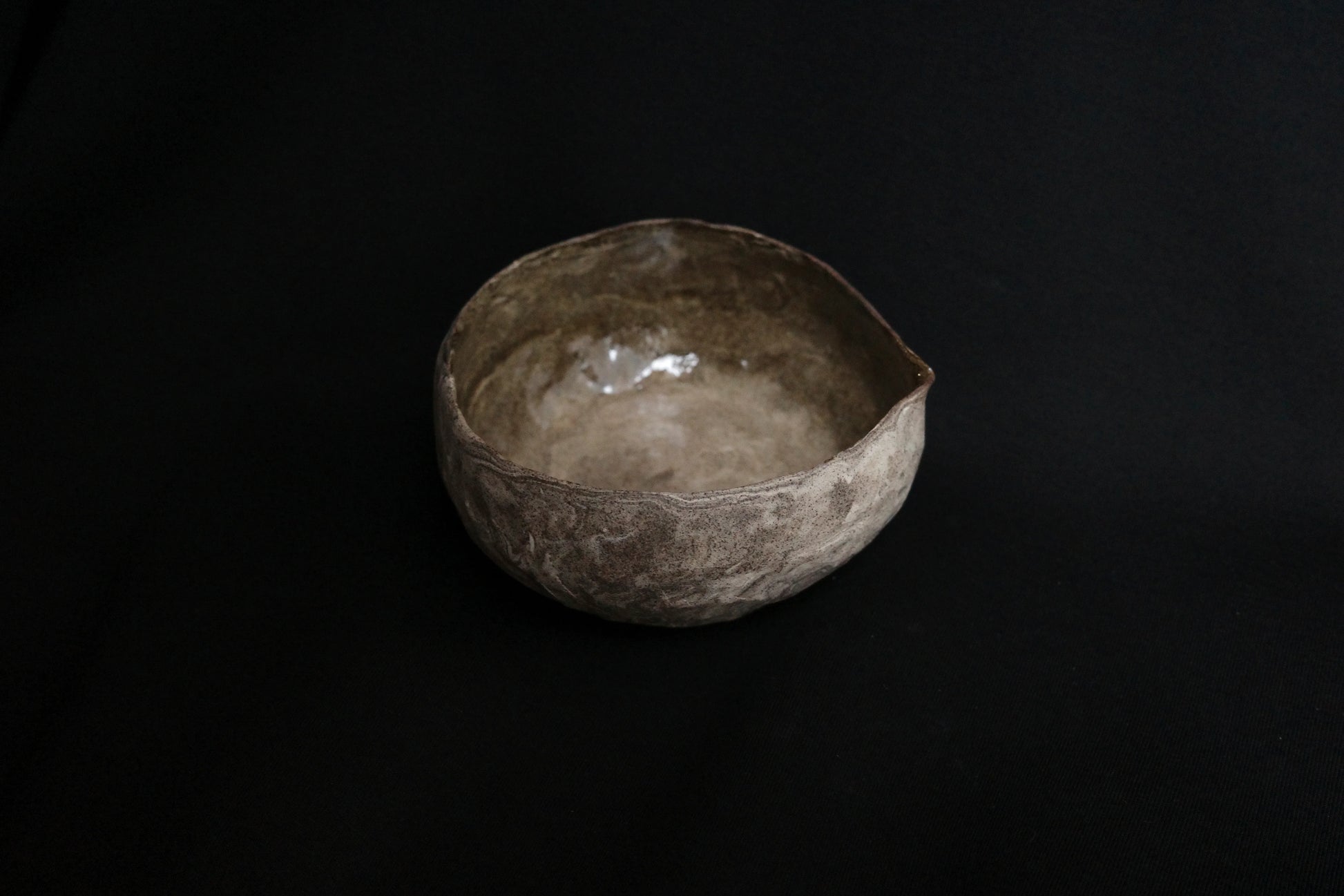 Handcrafted ceramic bowl with rustic, textured finish on a black background