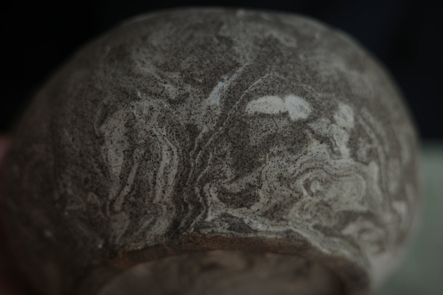 Close-up of handcrafted ceramic bowl with marbled gray and white textured surface