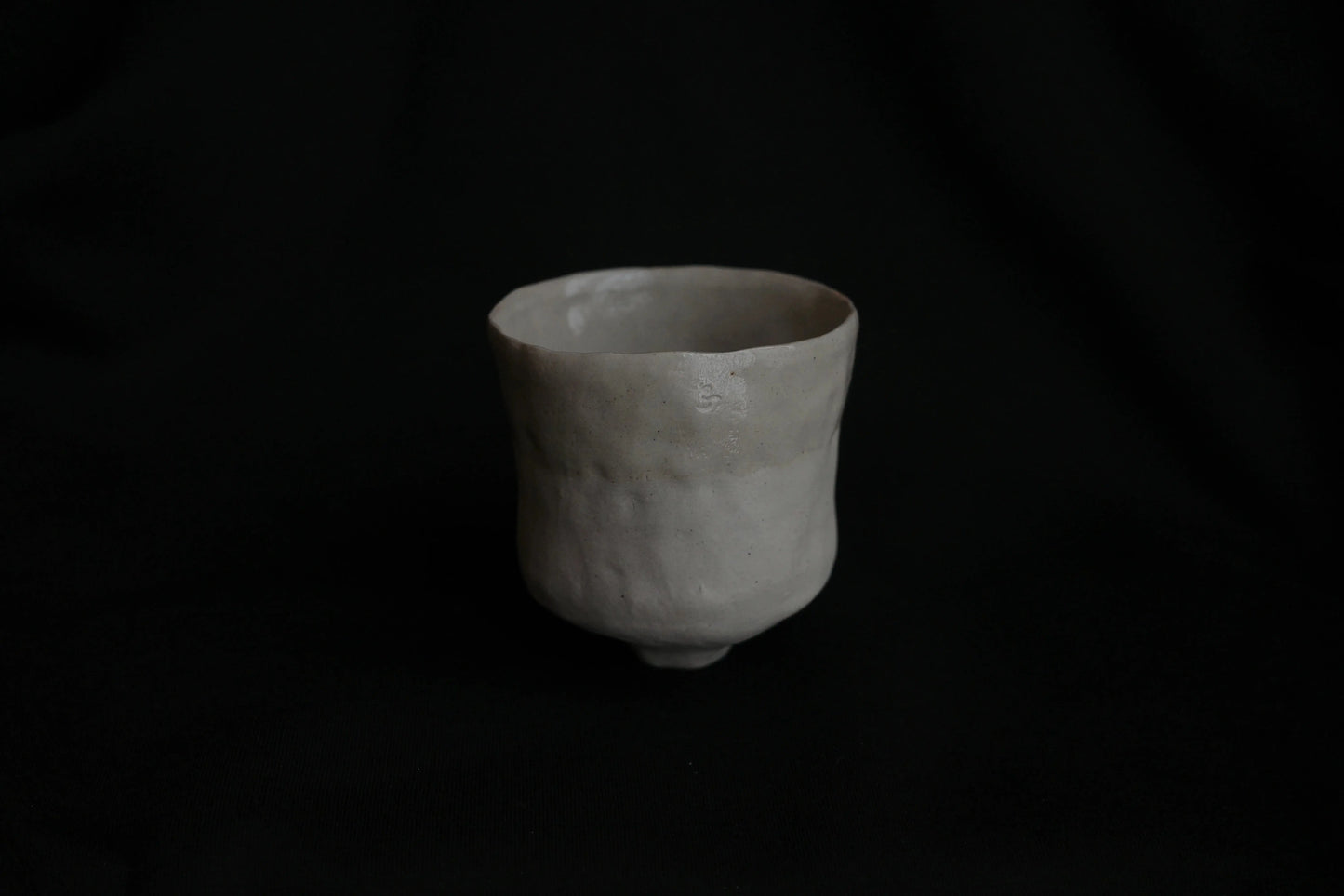Handcrafted minimalist ceramic cup with natural texture on black background