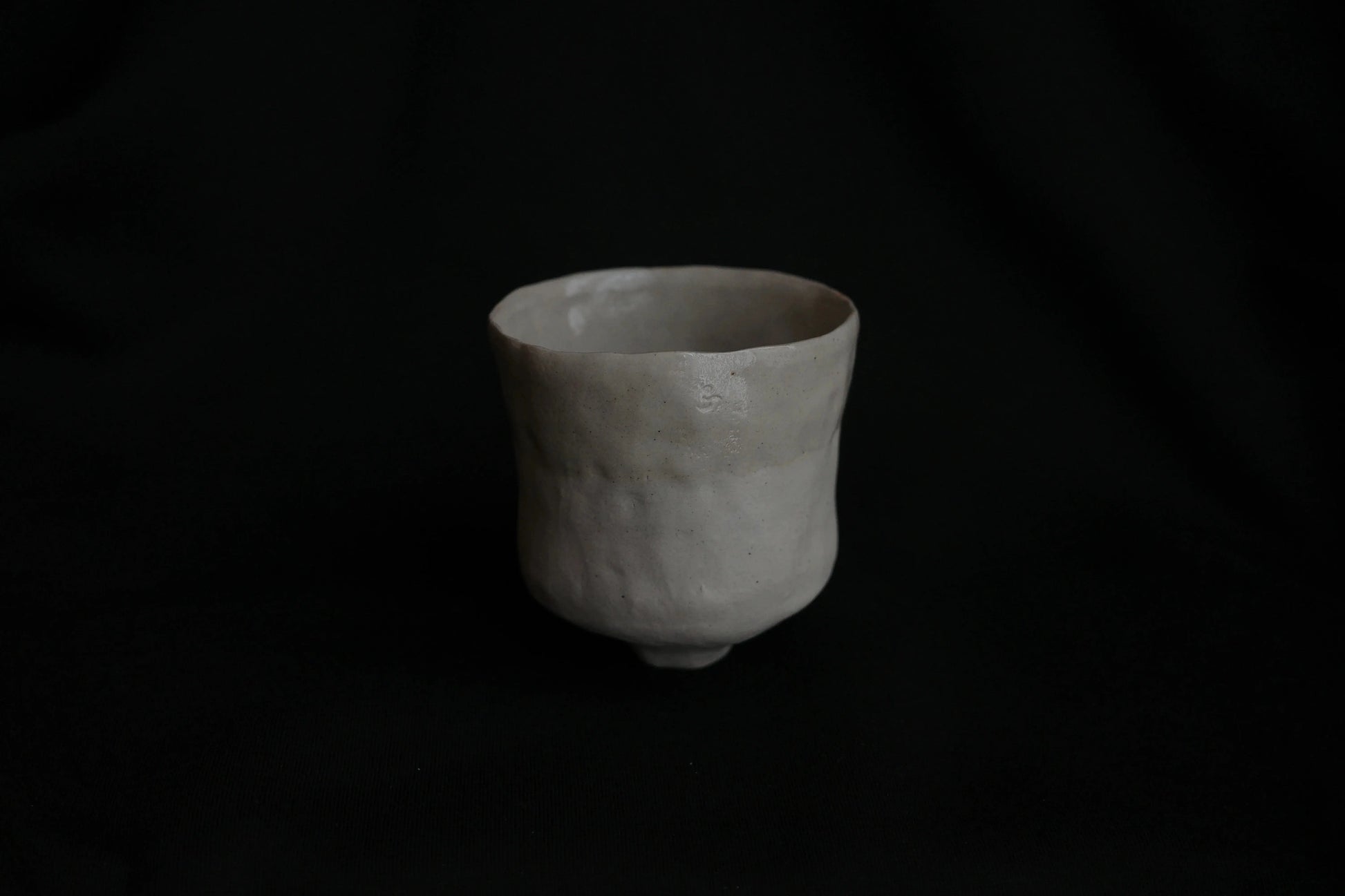 Handcrafted minimalist ceramic cup with natural texture on black background