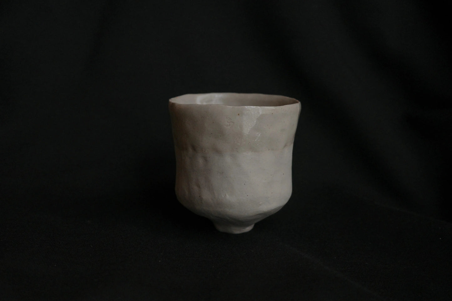Handcrafted ceramic cup with minimalist, organic shape on black background