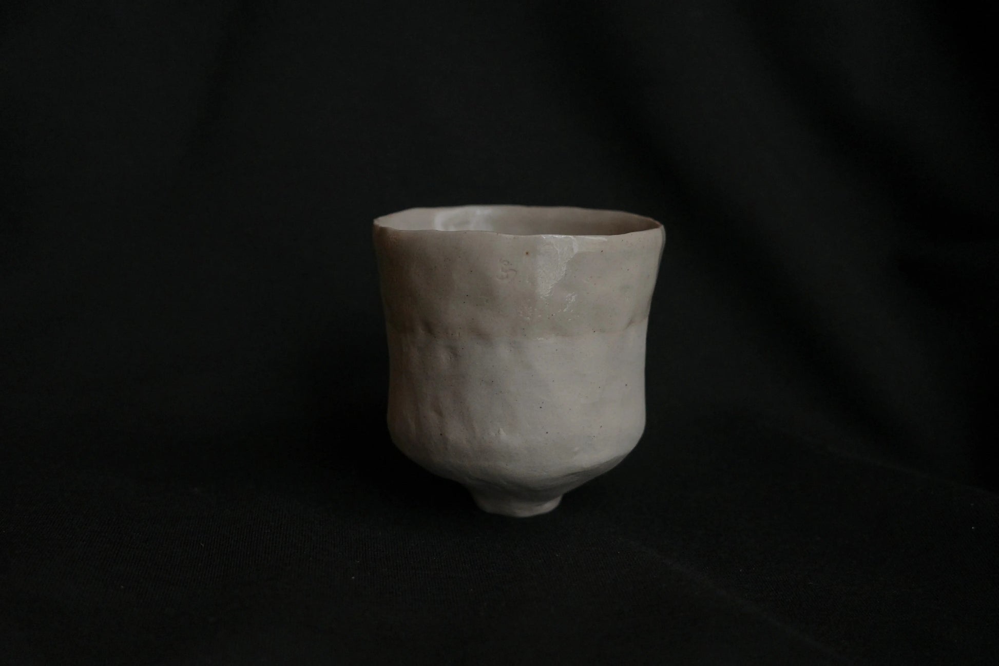 Handcrafted ceramic cup with a minimalist, organic design on a black background