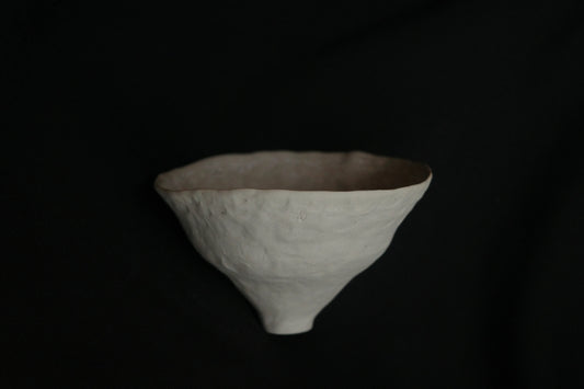 Handcrafted minimalist ceramic bowl with textured surface on black background