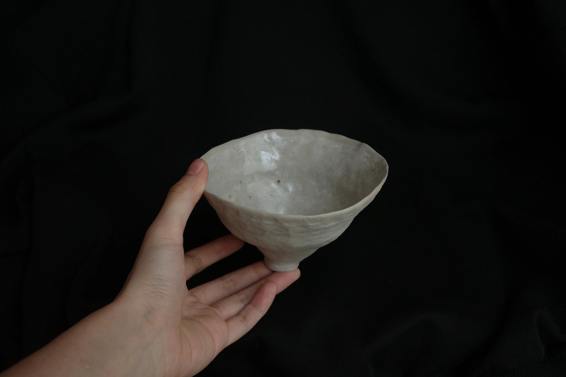 Hand holding a handcrafted minimalist ceramic bowl with textured white glaze