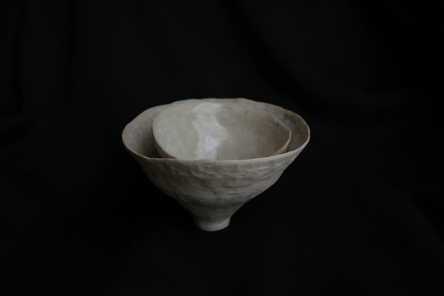 Handcrafted ceramic nesting bowls with minimalist design on a black background