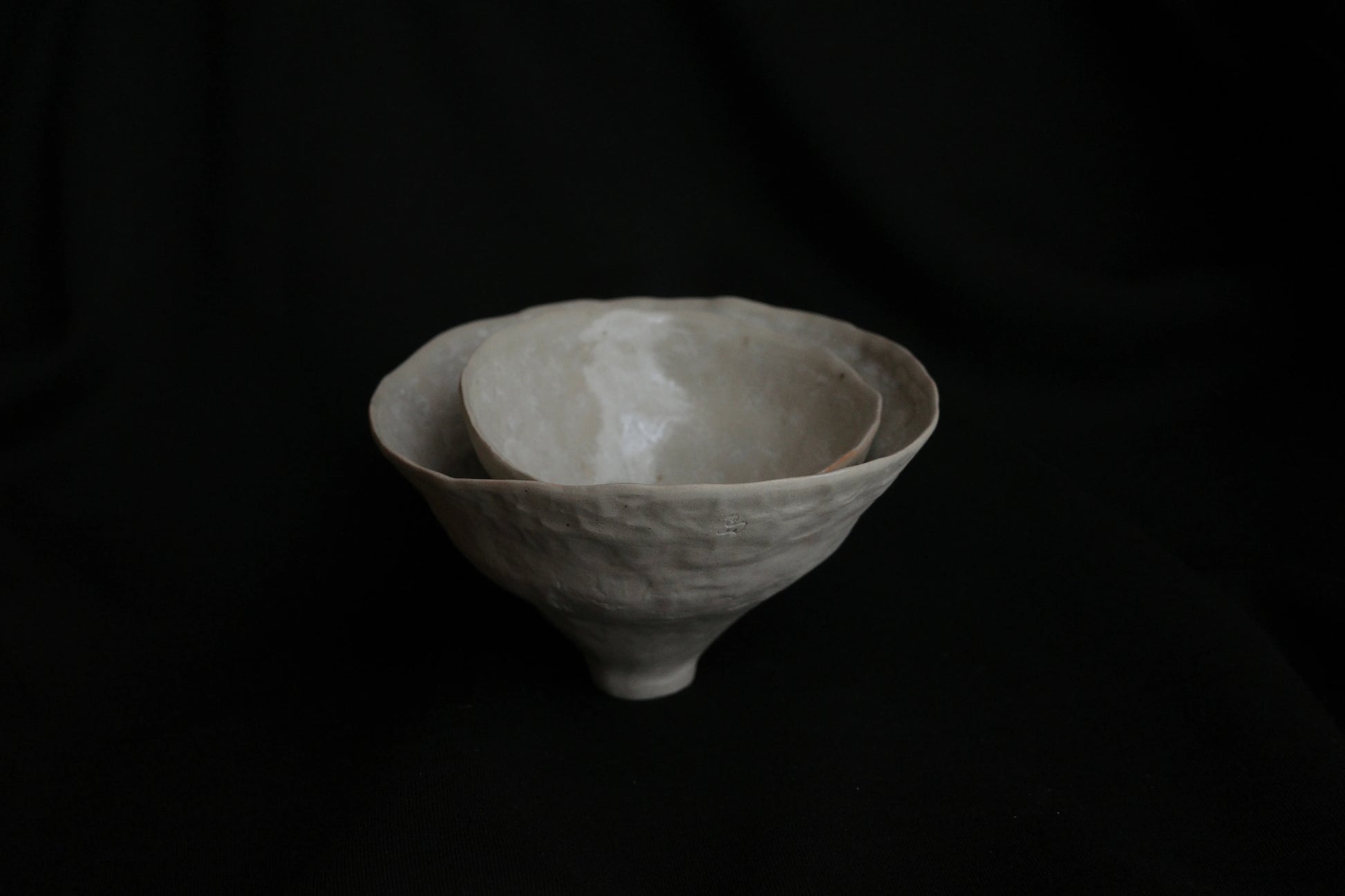 Handcrafted ceramic nesting bowls with minimalist design on a black background